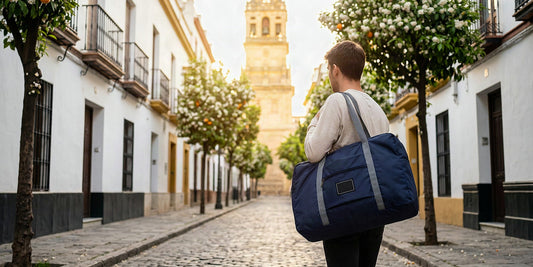 Voyageur avec un sac de voyage pliable sous les orangers en fleurs d'une ruelle de Séville en mars